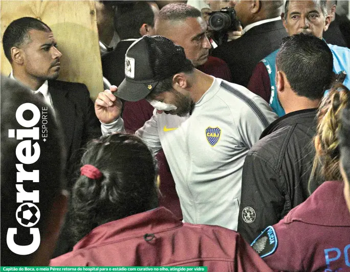  ??  ?? Capitão do Boca, o meia Pérez retorna do hospital para o estádio com curativo no olho, atingido por vidro