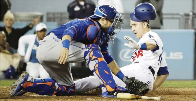  ??  ?? LOS ANGELES: Los Angeles Dodgers’ Chase Utley, right, slides into home plate to score on a single by Justin Turner as New York Mets catcher Travis d’Arnaud fields the throw during the sixth inning of a baseball game, Monday, in Los Angeles. —AP