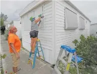  ?? AP PHOTO/WILFREDO LEE ?? Chris Nagiewicz, left, watches as his wife Mary screws in a hurricane panel on a trailer home Saturday in Briny Breezes, Fla.