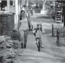  ?? RJ Sangosti, The Denver Post ?? Katherine Murphy, left, walks as her daughter, Alysa Murphy, 5, bikes to Dora Moore Elementary School on Bike to School day on May 9.