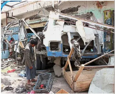  ??  ?? Devastatin­g attack: A Yemeni child getting a closer look at the destroyed bus near the Dahyan market that killed at least 29 children. — AFP