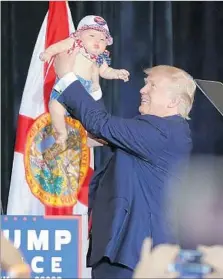  ?? Chip Somodevill­a Getty Images ?? DONALD TRUMP lifts a baby in Tampa, Fla., on a hectic day that also took him to North Carolina, Nevada and Colorado.