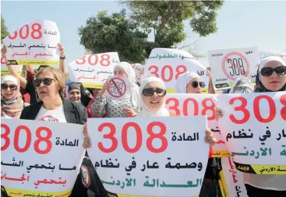  ?? AP ?? Women activists protest in front Jordan’s parliament in Amman on Tuesday with banners calling on legislator­s to repeal a provision that allows a rapist to escape punishment if he marries his victim. —