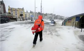  ?? Photograph: Finnbarr Webster/Alamy ?? A postal worker makes deliveries along Weymouth beach in Dorset.