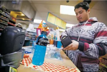  ?? LUIS SÁNCHEZ SATURNO/THE NEW MEXICAN ?? Daniel M. Romero of Santa Fe buys a Powerade on Wednesday at the Allsup’s Convenienc­e Store on North Guadalupe Street and Paseo de Peralta. A state senator wants to study the potential benefits and negative impacts of a statewide tax on sodas and other...