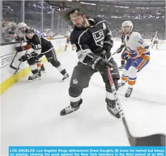  ??  ?? LOS ANGELES: Los Angeles Kings defenseman Drew Doughty (8) loses his helmet but keeps on playing, clearing the puck against the New York Islanders in the third period of an NHL hockey game in Los Angeles. — AP