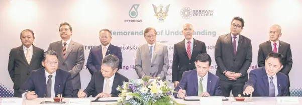  ?? ?? Abang Johari (standing, centre) witnessing the MoU signing between PCG and Sarawak Petchem.