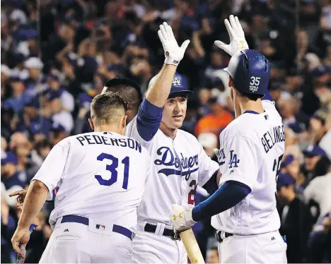  ?? HARRY HOW/GETTY IMAGES ?? Los Angeles Dodgers second baseman Chase Utley celebrates with teammates Joc Pederson and Cody Bellinger after scoring a run during the sixth inning against the Houston Astros in Game 6 of the World Series Tuesday at Dodger Stadium. L.A. won 3-1 to...