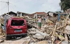  ?? Rangga Firmansyah/Associated Press ?? A resident of Cianjur, Indonesia, walks on the rubble of houses that were shattered by Monday’s 5.6 magnitude earthquake.