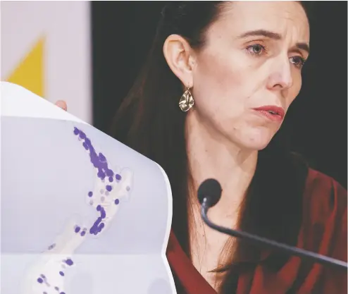  ?? ROBERT KITCHIN / POOL PHOTO VIA THE ASSOCIATED PRESS ?? New Zealand Prime Minister Jacinda Ardern holds a map of the nation at a COVID-19 update press conference
in Wellington on Monday as she announces a strict nationwide lockdown until at least Friday.