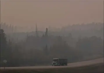  ?? JEN OSBORNE — THE NEW YORK TIMES ?? A thick layer of smoke from wildfires blankets a road in Fox Creek, Alberta, Canada, on May 18, 2023. Only 10countrie­s and territorie­s out of 134achieve­d the World Health Organizati­on's standards for a pervasive form of air pollution last year, according to air quality data compiled by IQAir, a Swiss company.