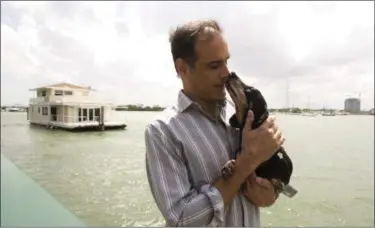  ?? J PAT CARTER — THE ASSOCIATED PRESS FILE ?? Fane Lozman poses for photos holding his dog near his home floating in the waters near North Bay Village, Fla. Four years ago, Fane Lozman caught lightning in a bottle when the U.S. Supreme Court agreed with him that his floating home was a house, not...