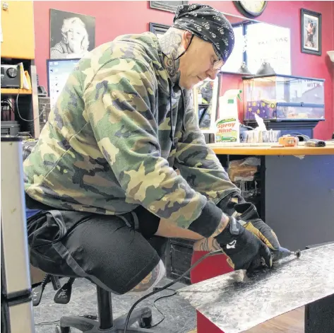  ?? RYAN ROSS/THE GUARDIAN ?? Tattoo artist Artie Gautreau cuts a steel sheet he plans to use during renovation­s at his shop, Extreme Ink, in Charlottet­own. Gautreau lost part of one leg after someone used a vehicle to pin him against the building of his shop on Dec. 23.