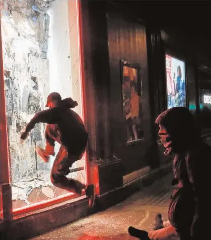  ??  ?? Un manifestan­te destroza el escaparate de una tienda, ayer en Barcelona
