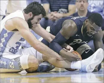  ?? Gerry Broome/Associated Press ?? Pitt’s Jared Wilson-Frame, right, struggles for possession of the ball in the first half of the Tar Heels’ 96-65 win Saturday in Chapel Hill. Nothing has come easy for the young Panthers this season, as they remain winless in the ACC.