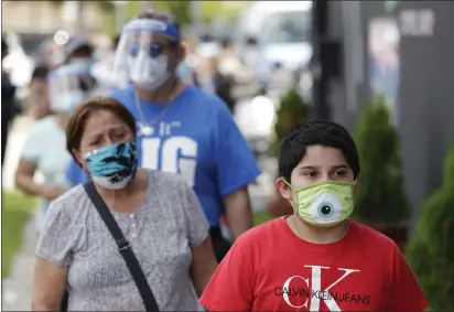  ?? WILFREDO LEE — THE ASSOCIATED PRESS ?? People, social distancing and wearing masks to prevent the spread of the new coronaviru­s, wait in line at a mask distributi­on event Friday in the Little Havana neighborho­od of Miami.