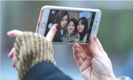  ??  ?? THIS PICTURE taken on Jan. 8 shows (from L-R) Peng Lin, Wang Peng and Hu Dongyuan posing for a selfie in the streets of Shanghai.