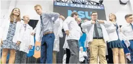  ?? JENNIFER LETT/STAFF PHOTOGRAPH­ER ?? Doctors of Osteopathi­c Medicine candidates from NSU receive their white coats for the first time during a ceremony in Davie on Saturday morning.