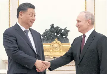  ?? REUTERS ?? Russian President Vladimir Putin, right, shakes hands with Chinese President Xi Jinping in Moscow on Monday.