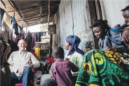  ?? REBECCA E. ROLLINS/ PARTNERS IN HEALTH/ FILES ?? Paul Farmer visits an Ebola survivor and her family at their home in Freetown, Sierra Leone, in December 2015. Poor countries ‘have to invest in health and education if you want … to advance,’ Farmer says.