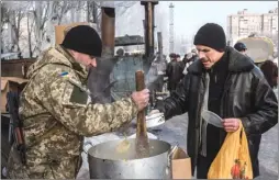  ?? The Associated Press ?? A Ukrainian serviceman gives free food to residents at the humanitari­an aid centre in Avdiivka, Ukraine, on Friday.