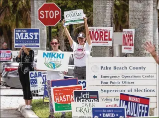  ?? DAMON HIGGINS / THE PALM BEACH POST ?? Volunteers hold up signs outside the Palm Beach County Supervisor of Elections office on Monday as people slowly straggled in to cast their votes throughout the afternoon. Florida now has more than 13 million citizens who are registered to vote in the Aug. 28 primary.