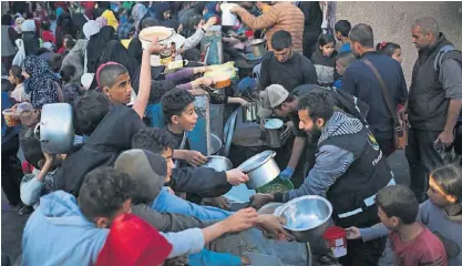  ?? ?? Palestinia­nos deslocados em Rafah tentam receber comida de organizaçõ­es não-governamen­tais.