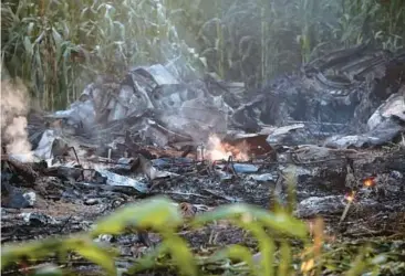  ?? GIANNIS PAPANIKOS/AP ?? A flame is seen amid debris of an Antonov cargo plane Sunday in Palaiochor­i village in northern Greece, after it reportedly crashed late Saturday near the city of Kavala. Experts who investigat­ed on Sunday found no evidence of dangerous substances but say there’s a lot of ordnance that the plane was carrying spread around the crash site.