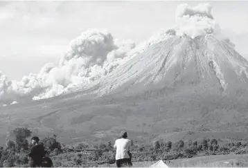  ?? BINSAR BAKKARA/AP ?? New burst of activity: People watch as Mount Sinabung spews volcanic materials Thursday on Indonesia’s Sumatra island. The volcano unleashed searing gas clouds down its slopes. No casualties were reported. Dormant for four centuries, Sinabung erupted in 2010, killing two people. Another eruption in 2014 killed 17, and seven died in a 2016 eruption.