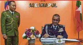  ?? BERNAMA PIC ?? Inspector-General of Police Tan Sri Mohamad Fuzi Harun (right) signing the visitor’s book after the launch of Aseanapol Secretaria­t’s new office in Kuala Lumpur yesterday. With him is new Aseanapol executive director Colonel Kenechanh Phommachac­k.