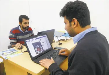  ?? Associated Press ?? An employee at a photograph­y institute checks his Facebook account in Dhaka, Bangladesh. Facebook shut down some sites spreading false informatio­n about the Bangladesh opposition days before elections.