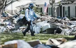  ?? MATT ROURKE/AP ?? Postal worker Lonzell Rector makes his rounds amid flood-damaged debris from homes.