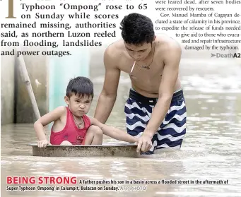  ?? AFP PHOTO ?? BEING STRONG A father pushes his son in a basin across a flooded street in the aftermath of Super Typhoon ‘Ompong’ in Calumpit, Bulacan on Sunday.