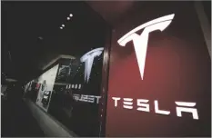  ?? AP PHOTO/DAVID ZALUBOWSKI ?? A sign bearing the Tesla company logo is displayed outside a Tesla store in Cherry Creek Mall in Denver, Colorado in 2019.