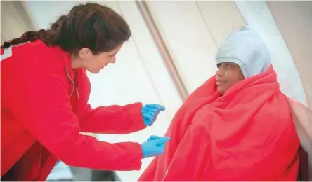  ?? — AFP ?? A migrant receives assistance from a Spanish Red Cross member upon her arrival aboard a Spanish coast guard boat at Tarifa’s harbour on Thursday.