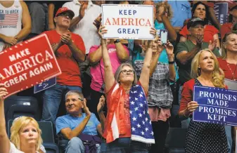 ?? Jayme Gershen / Bloomberg ?? Supporters hold placards as President Trump, not pictured, speaks during a campaign rally in Estero, Fla., on Wednesday. Could their support reflect a problem in our education system?
