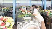  ?? PHOTOS BY SAKCHAI LALIT AP ?? Relatives of the victims of a mass killing attack adjust portraits on a coffin at Wat Si Uthai temple in the rural town of Uthai Sawan, northeaste­rn Thailand, on Saturday.