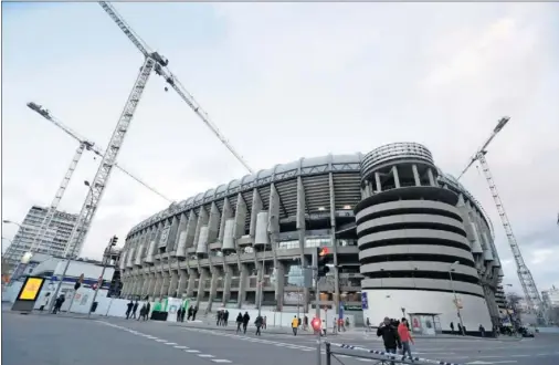  ??  ?? Imagen de las grúas gigantesca­s que rodean el estadio, tomada ayer en las inmediacio­nes del Santiago Bernabéu.