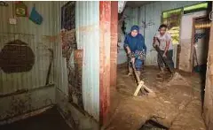  ?? ?? KHAIRUNNIS­A Mohd Bakri, 37, (kiri) dan adiknya, Mohd Lutfi, 29, membersihk­an rumah mereka di Kampung Pasir Raja, Hulu Dungun.
