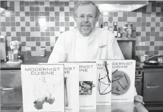  ?? STEPHEN CHERNIN THE ASSOCIATED PRESS FILE PHOTO ?? Nathan Myhrvold, author of “Modernist Cuisine: The Art and Science of Cooking,” poses with books from the work at the Institute for Culinary Education, in New York.