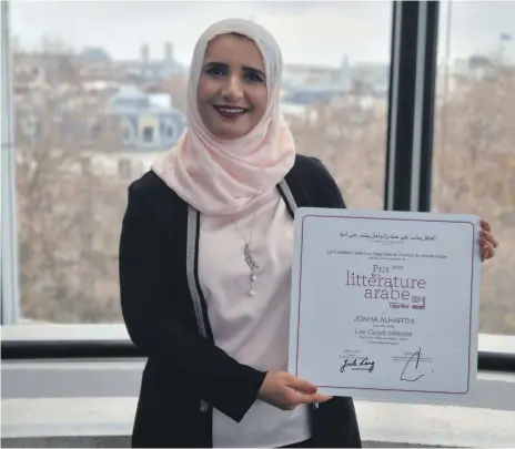  ?? Jokha Alharthi ?? Omani author Jokha Alharthi with her certificat­e from the Institute of the Arab World for ‘Celestial Bodies’