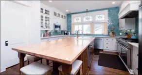  ??  ?? An aqua tiled accent wall and an expansive island add appeal to the kitchen.