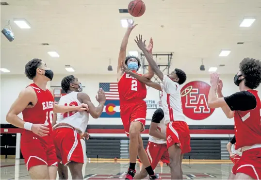  ?? Eli Imadali, Special to The Denver Post ?? Denver East’s Quis Davis shoots the ball as Corey Shively defends Wednesday during practice. The Colorado High School Activities Associatio­n recently required players to wear masks during games because of the COVID-19 pandemic.