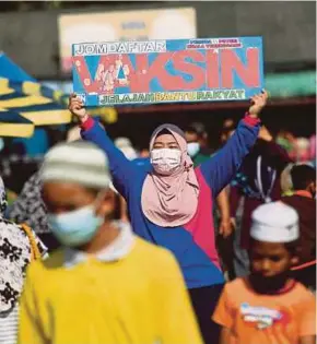  ?? PIC BY GHAZALI KORI ?? A volunteer holding up a sign to encourage the public to register for the National Covid-19 Immunisati­on Programme, in Kuala Terengganu on Friday.