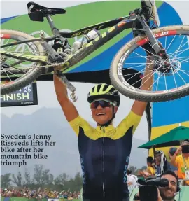  ??  ?? Sweden’s Jenny Rissveds lifts her bike after her mountain bike triumph