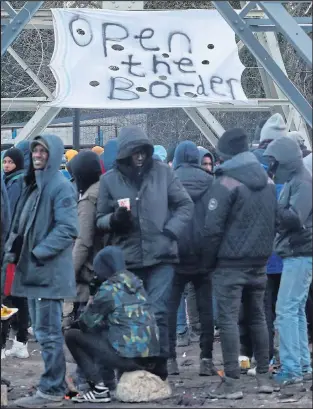  ?? Pictures: DENIS CHARLET / AFP, GARETH FULLER / PA ?? Migrants try to keep warm at their makeshift camp in the port town yesterday