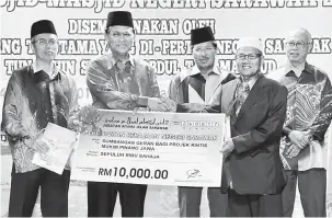  ??  ?? SUMBANGAN: Dr Rahman (dua kiri) menyerahka­n replika cek bernilai RM10,000 kepada wakil Masjid At-Taqwa, Kampung Pinang Jawa. Turut kelihatan (dari kiri) Ismail dan Misnu.