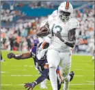  ?? Lynne Sladky The Associated Press ?? Miami running back Deejay Dallas leaves Virginia linebacker Charles Snowden in his wake on a 17-yard touchdown catch in the first quarter of the Hurricanes’ 17-9 win Friday at Hard Rock Stadium.