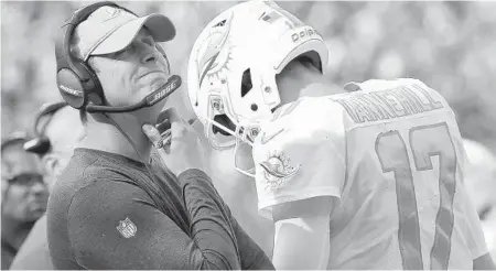  ?? STEVEN SENNE/AP ?? Dolphins coach Adam Gase, left, watches from the sideline as Ryan Tannehill walks past him during the second half of Sunday's game against the Patriots.