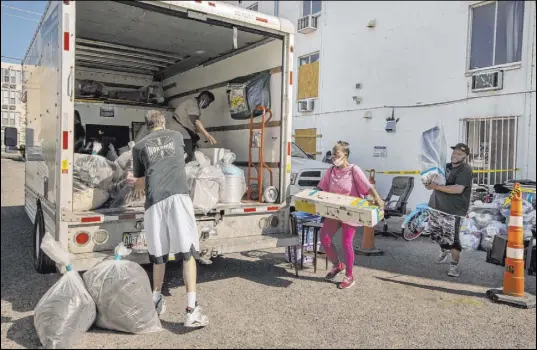  ?? L.E. Baskow Las Vegas Review-Journal @Left_Eye_Images ?? Former Alpine Motel resident Helen Clark, center, carries her possession­s and those of Audrey Palmer to a truck Thursday.